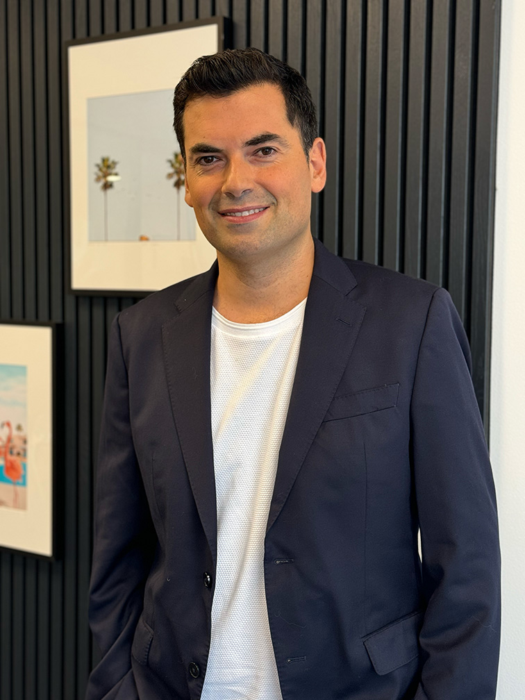 Portrait professionnel du Dr Emmanuel Elard, médecin esthétique spécialisé dans les injections d'acide hyaluronique, posant avec élégance devant un décor moderne.